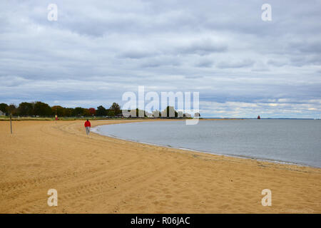 Paysage de lone man walking on beach avec un ciel nuageux Banque D'Images