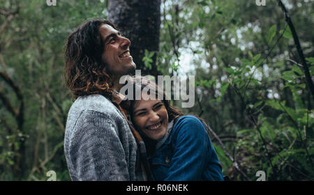 Belle femme embrassant son petit ami et souriant dans la forêt tropicale. L'homme et la femme ont beaucoup de temps en forêt durant la pluie. Banque D'Images