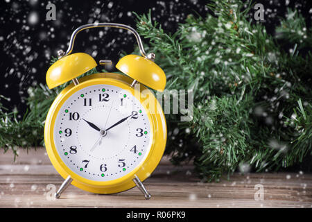 Belle horloge rétro et l'arbre de Noël en arrière-plan. Il neige. L'heure d'hiver image conceptuelle. Close up, selective focus Banque D'Images
