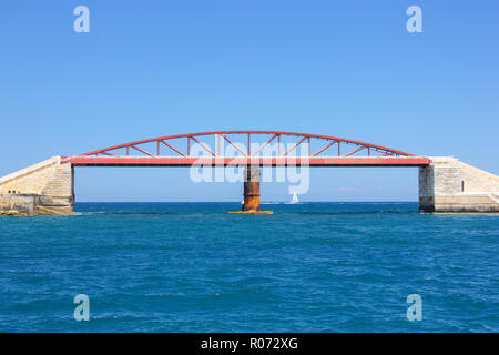 Petit navire voilier blanc en bleu de l'eau Grand Harbour, La Valette. Brise-lames métalliques du Pont rouge sur le premier plan de construction à sunny day Banque D'Images