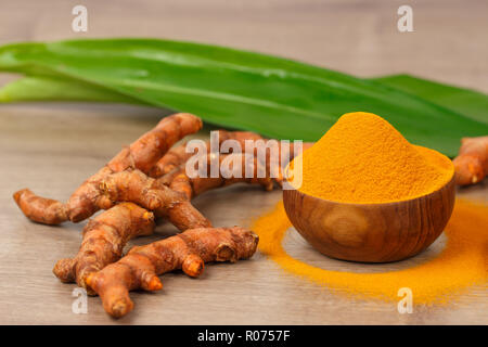 Poudre de curcuma dans bol en bois et le curcuma frais sur la vieille table en bois. Épices indiennes Banque D'Images