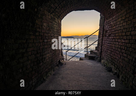 Le soleil levant par peeps une petite bande de tunnel à Charlestown, Cornwall. Ce tunnel aurait été une partie cruciale du port. Banque D'Images