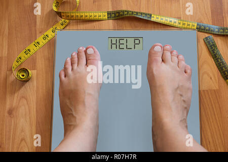 Pieds gonflés de femme sur l'échelle de pondération que demander de l'aide à perdre du poids. Tentation de régime pour perdre du poids ou concept Banque D'Images