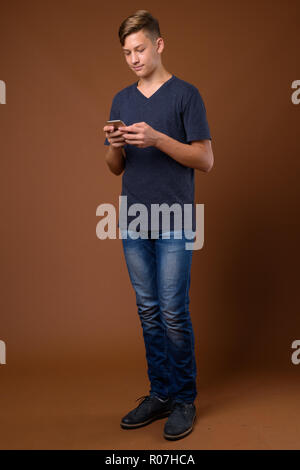 Studio shot of young handsome boy contre brown backgrou Banque D'Images