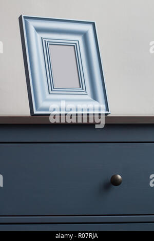 Voir le détail avant verticale de square d'épaisseur sur cadre photo en bois vintage bleu commode avec poignées noires contre le mur dans la lumière naturelle copie Banque D'Images