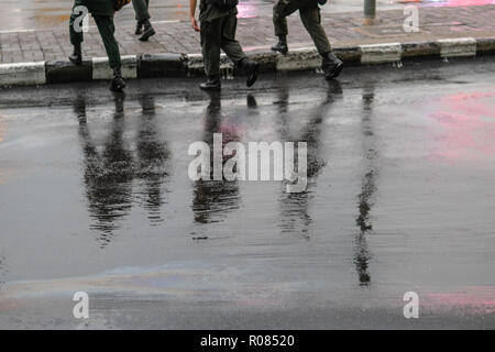 La réflexion de personnes à pied sur route mouillée en jour de pluie Banque D'Images