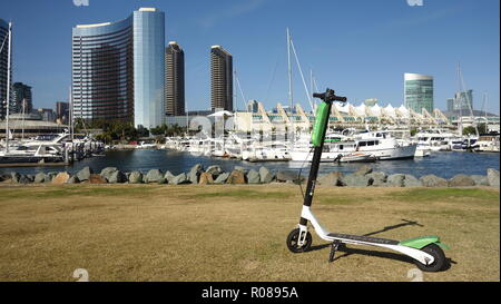 Close up of a green Lime-S Limebike dockless scooter électrique à louer au centre-ville de San Diego, avec vue partielle sur la ville et port de plaisance dans l'arrière-plan Banque D'Images