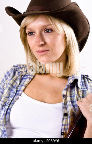 Closeup portrait de jolie femme occidentale en chemise et chapeau de cow-boy Banque D'Images