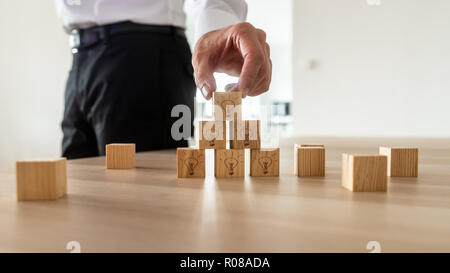 Vision de l'entreprise concept -man organisant des cubes en bois avec les icônes d'ampoule sur le bureau. Banque D'Images