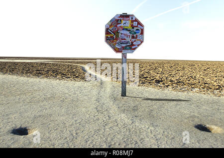 La photographie conceptuelle d'un panneau d'arrêt couverts en autocollants en face du chemin d'accès dans le bassin de Badwater, Death Valley National Park Banque D'Images