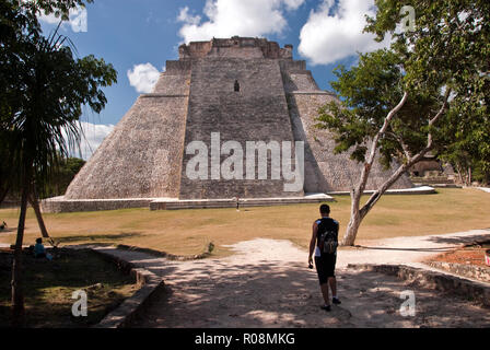 Les touristes voir la Pyramide du Magicien (Piramide del Adivino), une pyramide à méso-américain dans la Ville précolombienne d'Uxmal, Mexique. Banque D'Images