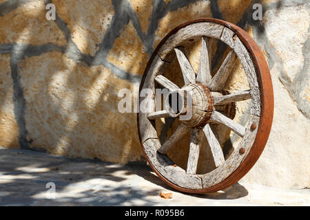 Roue en bois appuyée contre le mur de pierre Banque D'Images