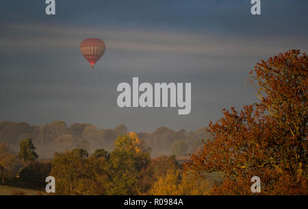 19/10/18 un ballon à air chaud s'élève au-dessus de champs brumeux entouré par de superbes couleurs d'automne près de Parwich dans le Derbyshire Peak District. Tous droits Banque D'Images