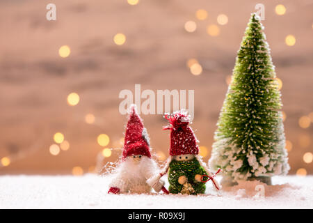 Sybolic avec paysage nature conceptuelle, un seul arbre de Noël vert et Petit Père Noël debout dans la neige sur un fond de lumières Banque D'Images