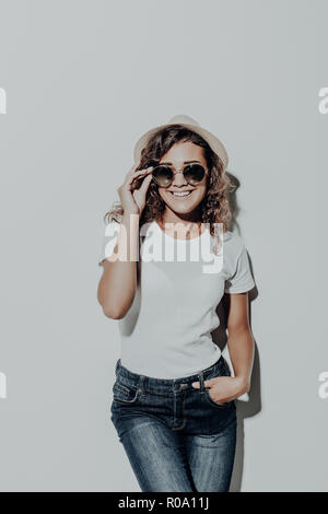 Portrait de femme latine bouclés en vêtements d'été occasionnels à chapeau brun isolé sur fond blanc. Banque D'Images