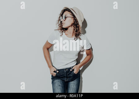 Portrait de femme latine bouclés en vêtements d'été occasionnels à chapeau brun isolé sur fond blanc. Banque D'Images