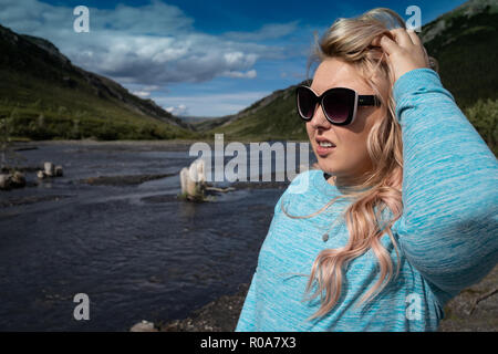 Femelle blonde se trouve près de la rivière sauvage dans le parc national Denali, poser et regarder le paysage de l'Alaska Banque D'Images