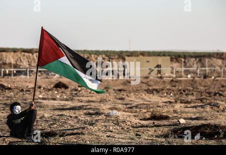 Un manifestant palestinien vu assis tout en tenant un drapeau pendant les affrontements dans l'Est de la ville de Gaza près de la frontière israélienne. Banque D'Images