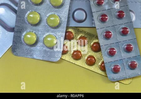 Comprimé rond jaune, brun, rouge foncé comprimés comprimés dans un paquet sur fond jaune Banque D'Images