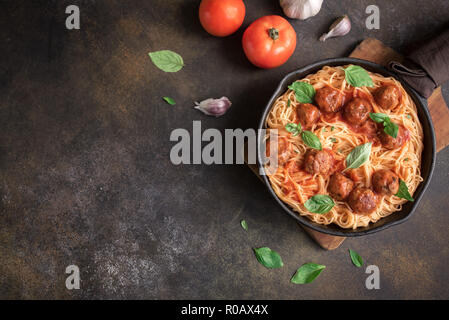 Les pâtes Spaghetti aux Boulettes de viande, sauce tomate et basilic frais dans la poêle en fonte. Les pâtes italiennes faites maison saine sur fond rustique avec copie espace. Banque D'Images
