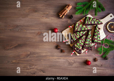 Brownies au chocolat en forme d'arbres de Noël avec glaçage vert et festif sur sprinkles table en bois, vue du dessus, copiez l'espace. Noël fait maison douce Banque D'Images