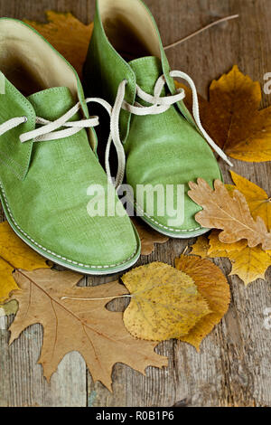 Paire de bottes en cuir vert et jaune des feuilles sur un vieux plancher en bois Banque D'Images