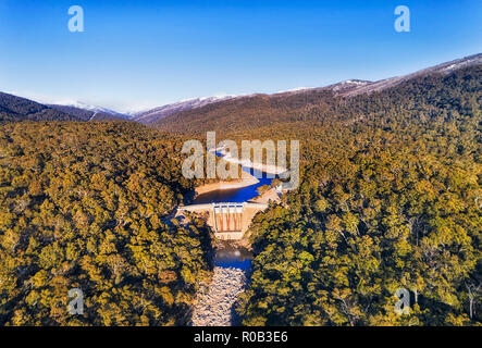 Montagnes de neige Snowy River bloqué par le barrage de Guthega dans d'épaisseur de neige evergreen-gum woods vu de dessus sur la rivière à sec contre la neige lointaine pe Banque D'Images