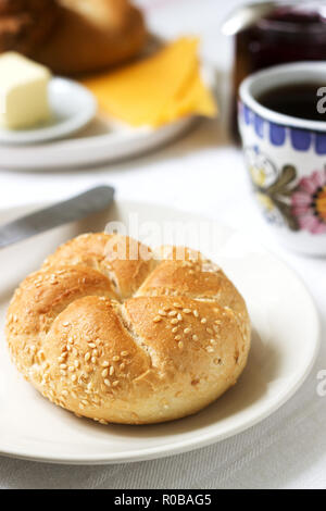 Le petit-déjeuner avec les pains Kaiser, de cassis confiture, beurre et fromage et thé. Focus sélectif. Banque D'Images