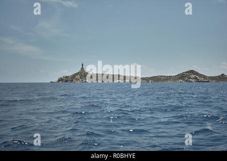 Marin avec un phare au loin vu de la mer sous un ciel d'été. Banque D'Images