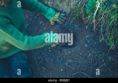 Un jardinier est creuser un trou autour d'un metal spike Banque D'Images