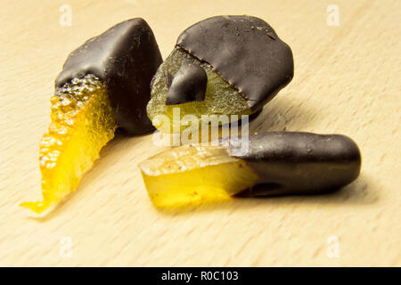 De délicieux chocolats chocolat noir à la poire, orange et gingembre sur le dessus d'une planche à découper en bois Banque D'Images