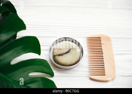 Eco friendly naturel bar shampooing solide en bois, brosse, savon, lotion vert sur blanc en bois avec feuilles de monstera vert. Eco produits plastique gratuitement. Banque D'Images