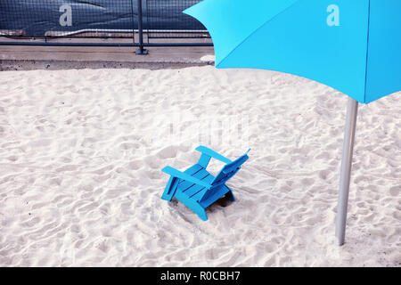 Chaise en plastique bleu cyan et parapluie en plastique sur le sable blanc de la plage. Vue du haut vers le bas. Banque D'Images