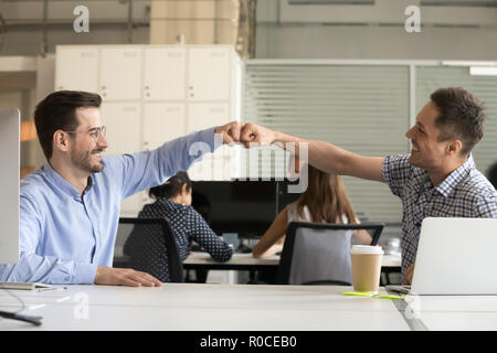 Friendly smiling collègues masculins fist bumping célébrer bon t Banque D'Images