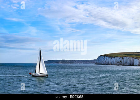 Yacht à voile dans la Manche au large des falaises blanches en eau calme avec ciel bleu et quelques nuages. Banque D'Images