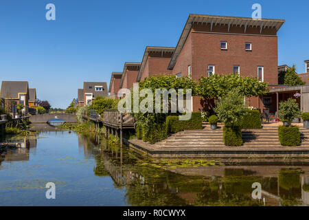 Rue de famille de classe moyenne écologique maisons avec jardin sur la rive d'un canal en Kloosterveen Assen, Pays-Bas Banque D'Images