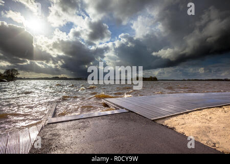 Nuages sombres et vent fort modéré élevé vagues se brisant sur un débarcadère quand une tempête s'en vient en plus d'un Dutch lake Banque D'Images