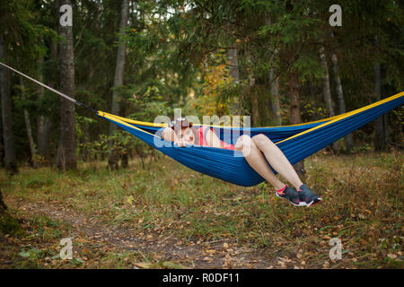 Photo de young woman lying in hammock in woods Banque D'Images