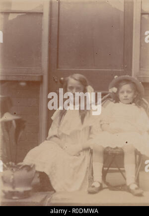 Vintage Edwardian Carte postale photographique d'un assis deux jeunes filles Banque D'Images