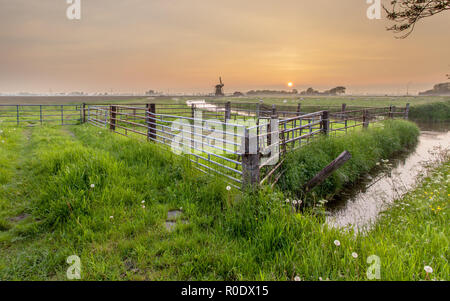 Paysage hollandais avec moulin et clôtures pendant le coucher du soleil, Groningen, Pays-Bas Banque D'Images