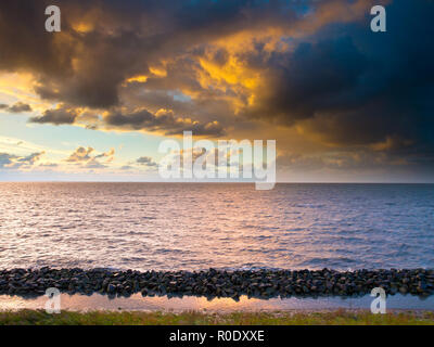 Fond coucher de soleil sur la mer de Wadden vu de l'Afsluitdijk avec brise-lames sur le premier plan Banque D'Images