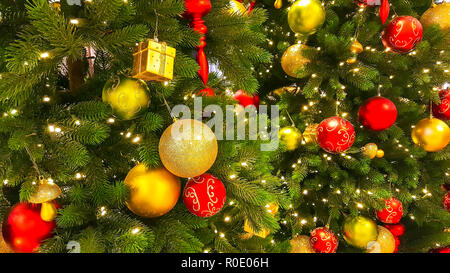 Close-up d'un arbre de Noël décoré avec des boules rouges et jaunes. Maison de vacances lumineuse arrière-plan. Banque D'Images