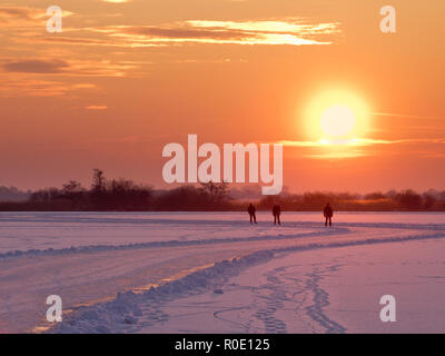 Patineurs de vitesse sont aproaching tandis que le soleil se couche sur le lac en hiver néerlandais Banque D'Images
