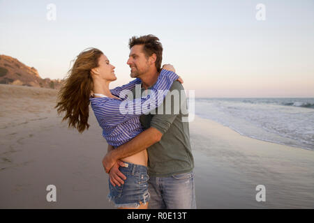 Portrait de demi-longueur Mid-Adult couple romantique dans les bras de l'autre at Beach Banque D'Images