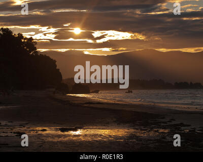 Un beau coucher du soleil doré sur une plage de sable à pakawau Nouvelle-Zélande Banque D'Images