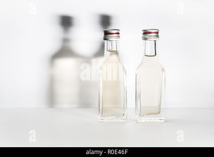 Deux bouteilles d'alcool vintage avec des ombres sur le mur. Banque D'Images