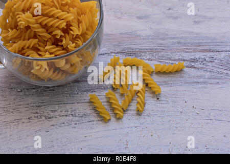 Macaroni cru dans un bol en verre à fond en bois blanc Banque D'Images
