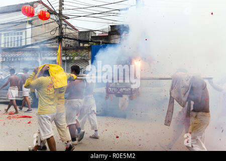 La ville de Phuket, Thaïlande, Octobre 09, 2016 : les dévots sont taoïste exerçant son palanquin contenant une idole, sous les explosions de pétards au cours de vegeta Banque D'Images