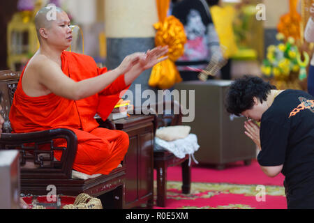 SANGKHLABURI, Thaïlande, le 24 janvier 2016 : un moine bouddhiste est une bénédiction en jetant une femme collier chapelet autour de son cou dans le Wat Banque D'Images