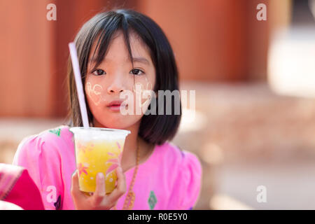 SANGKHLABURI, Thaïlande, le 24 janvier 2016 : Une petite fille tenant un soda est posant près d'un temple en Sanghlaburi, Thaïlande Banque D'Images